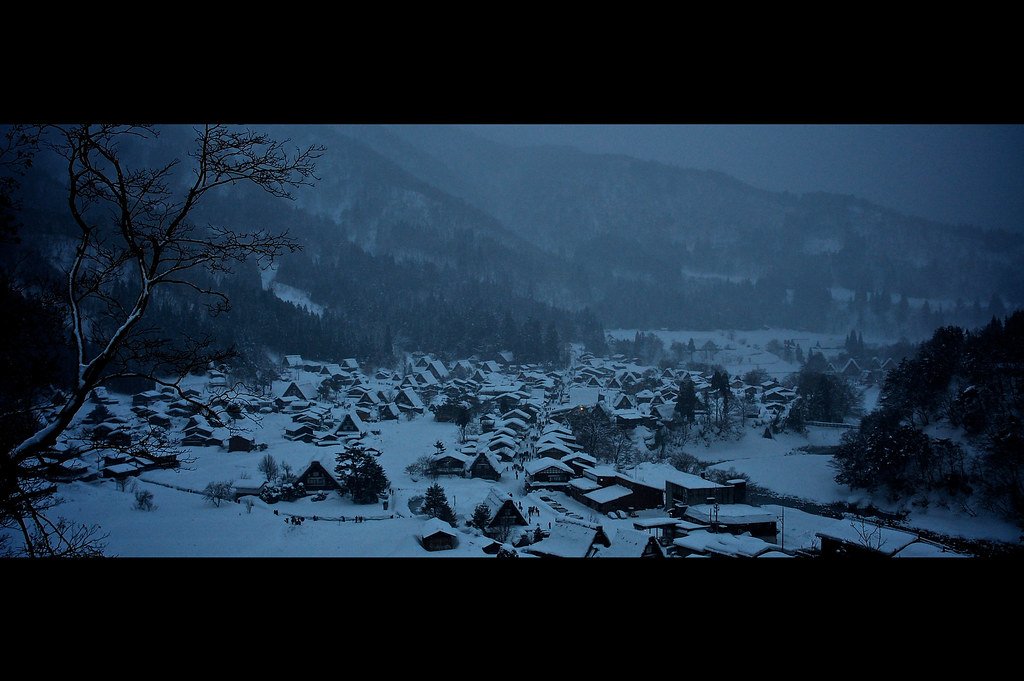 Verschneites Dorf Shirakawa-go vor dunklen Bergen